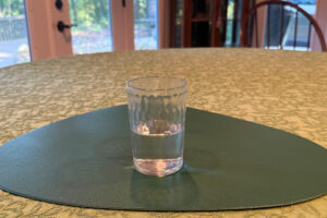 Photo of glass of water, half full, sitting on a kitchen table.